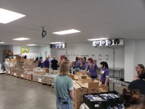 A group of volunteers examine a large line of foodstuffs stacked on pallets.